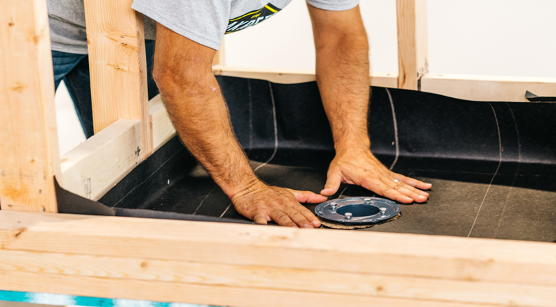 man installing dry pack shower pan